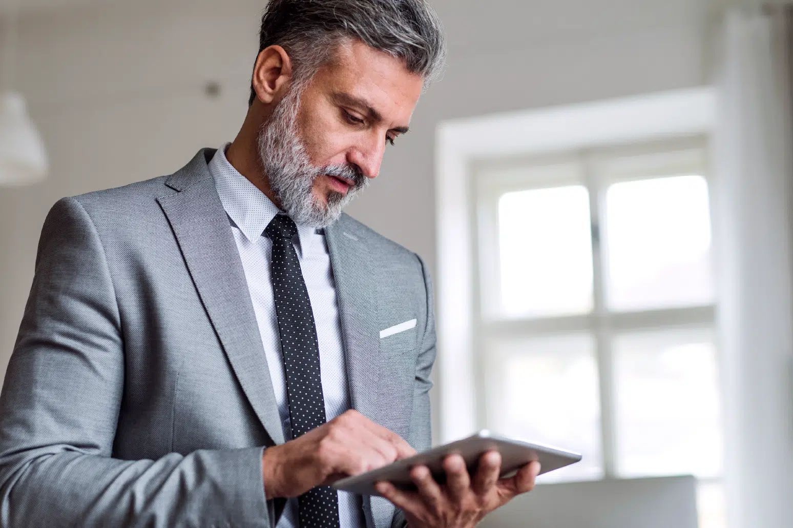 Image of a man in a suite looking at an iPad.