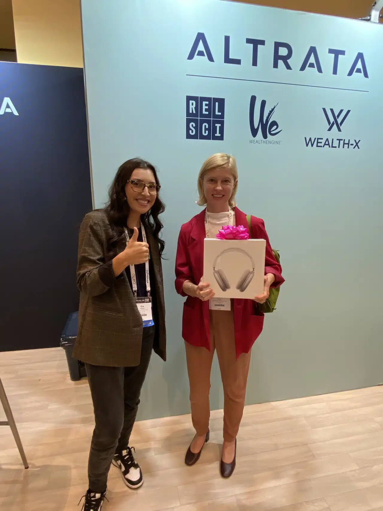 Two women standing in front of a booth during a conference