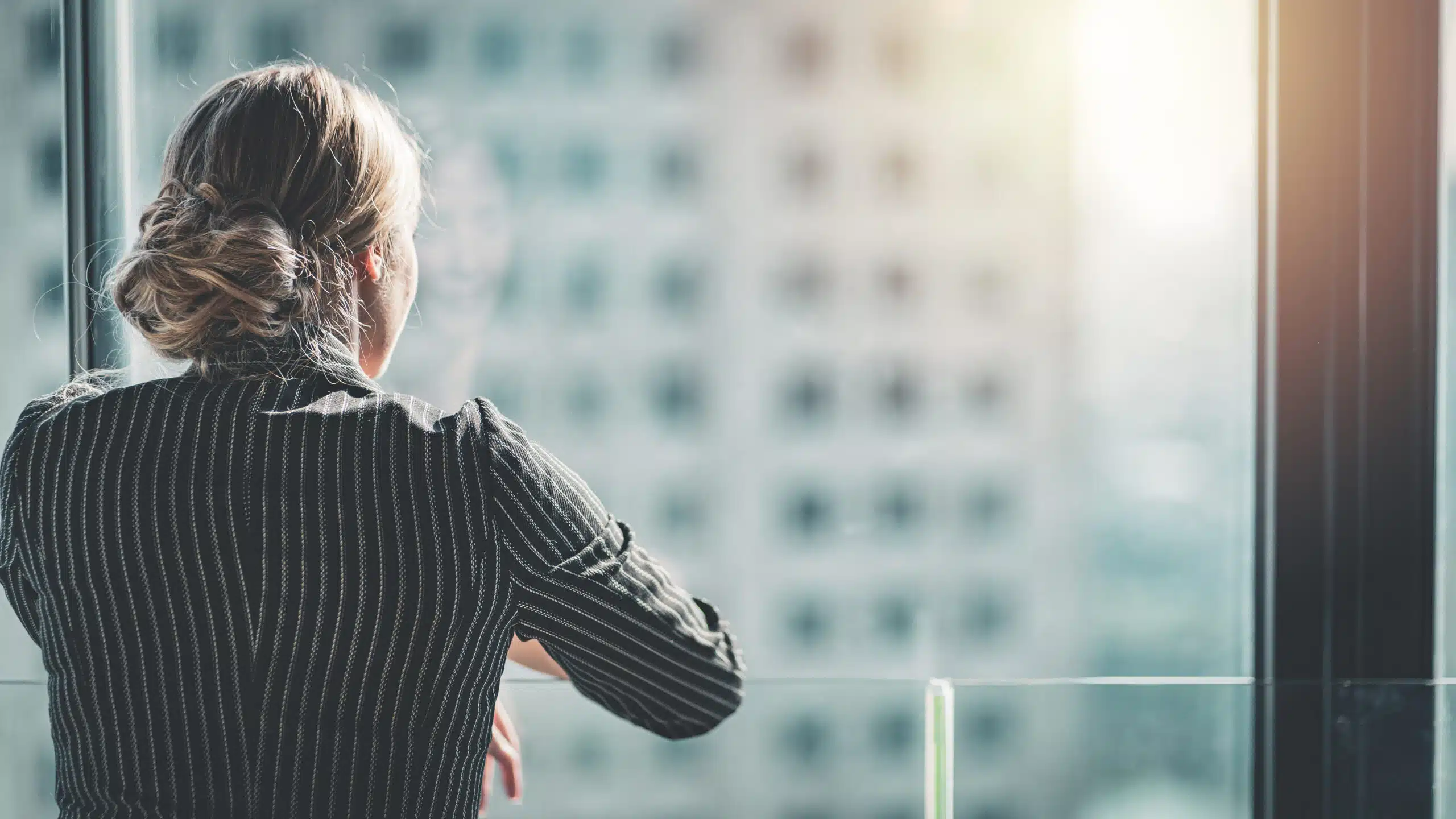 Female executive looks out the window of a high-rise office building