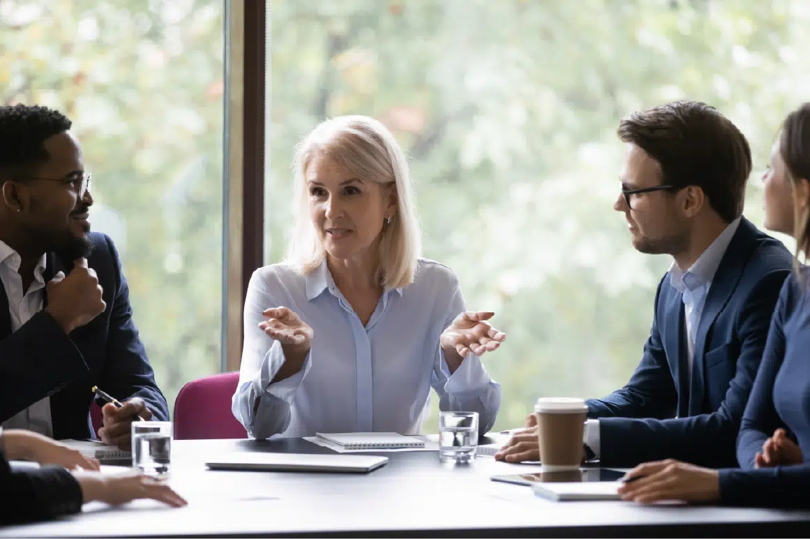 Woman smiling at a table speaking with her peers