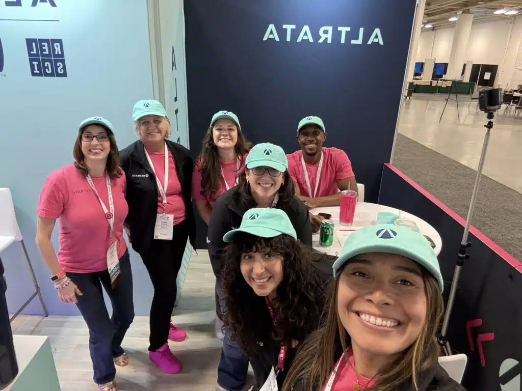 A group of people smiling together taking a selfie at a conference. 