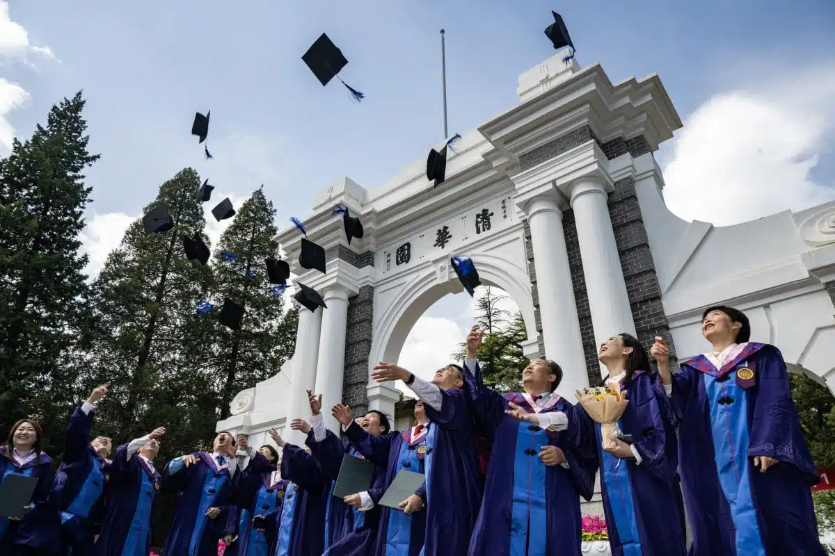 Students throw graduation caps into the air.