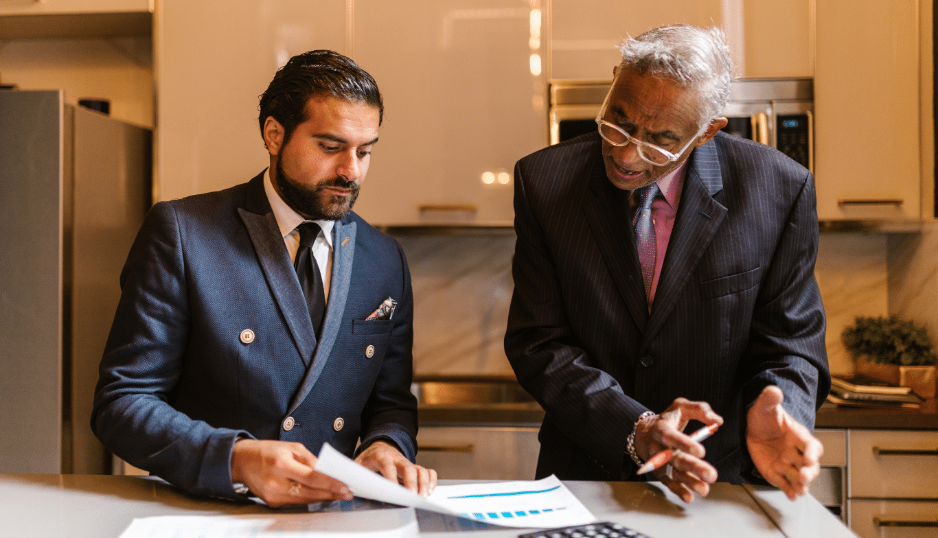 Men standing at a counter together discussing family office matters.