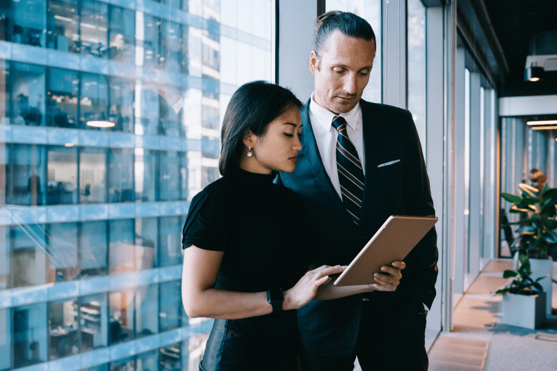 Two business professionals reviewing a clipboard in an office, representing executive turnover trends and leadership hiring decisions.