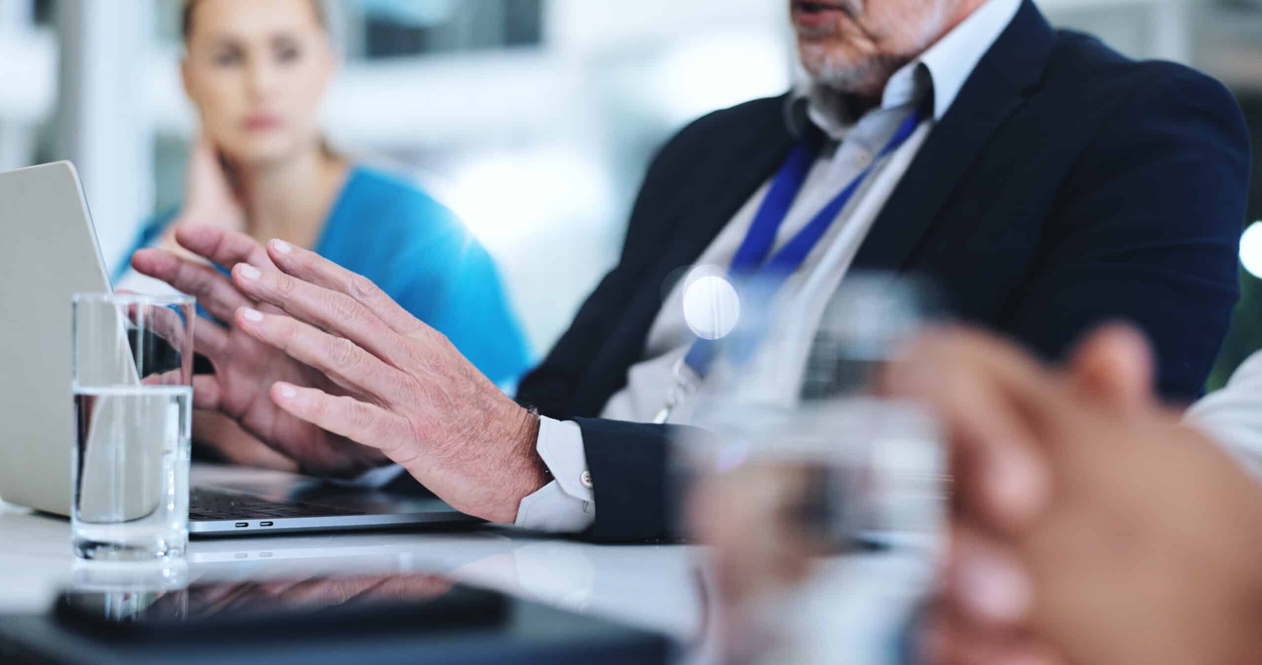 Wealth advisor reviewing prospect information on a laptop during a team meeting.