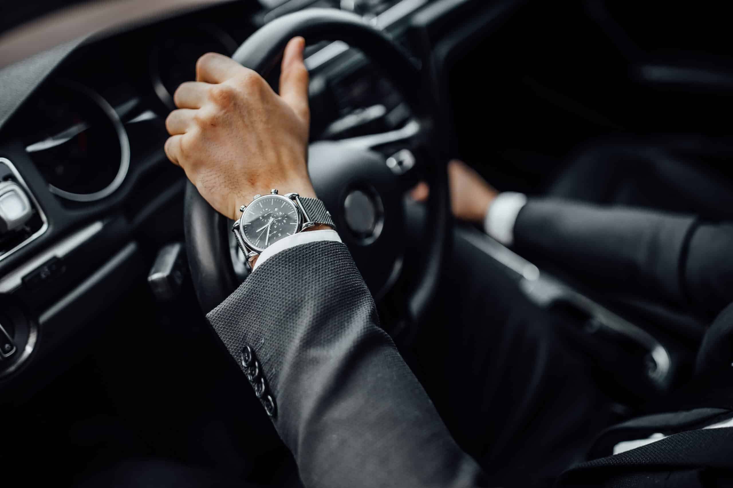 Luxury-clad driver wearing a wristwatch while driving a car